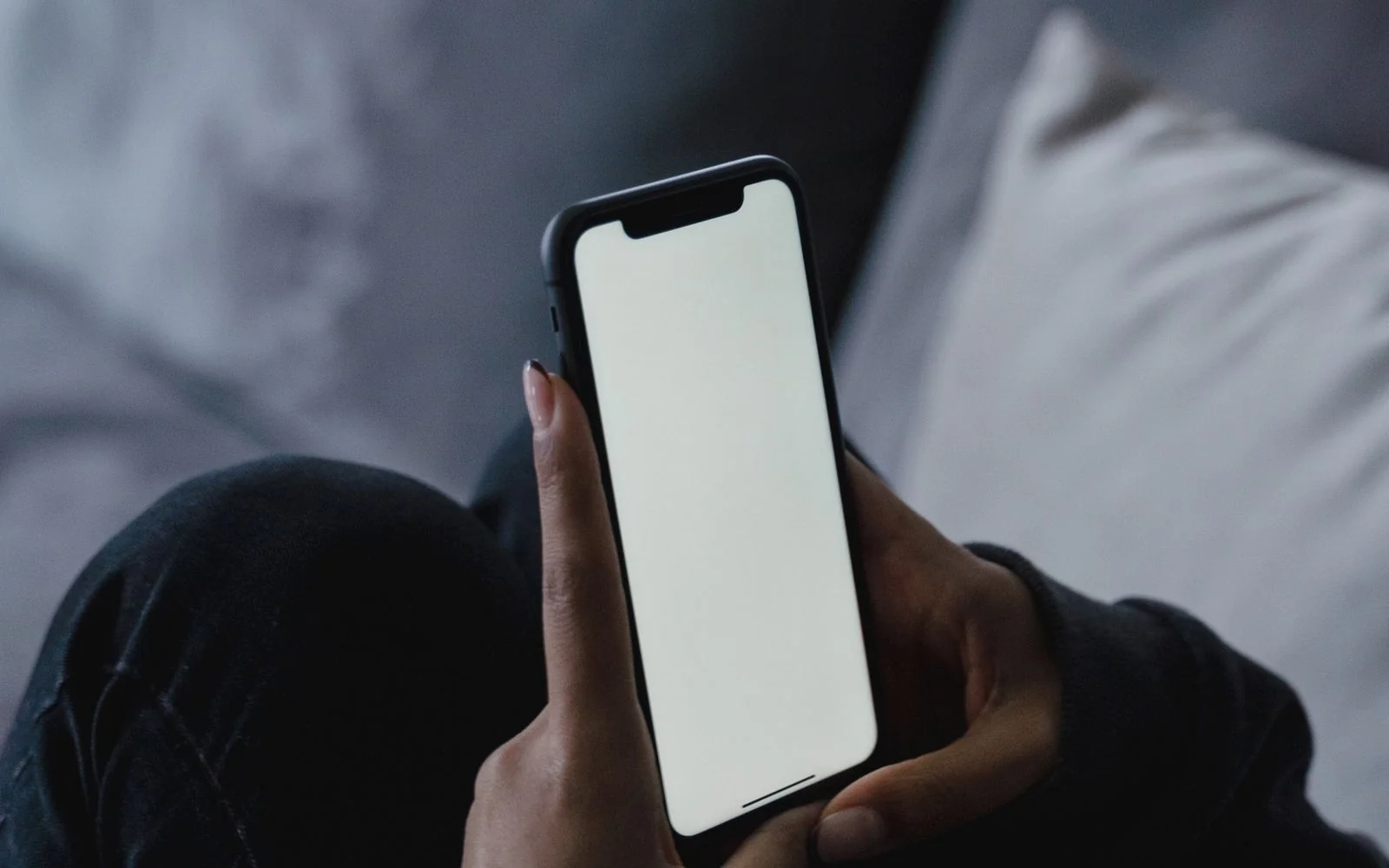 A person holding a smartphone with a blank screen