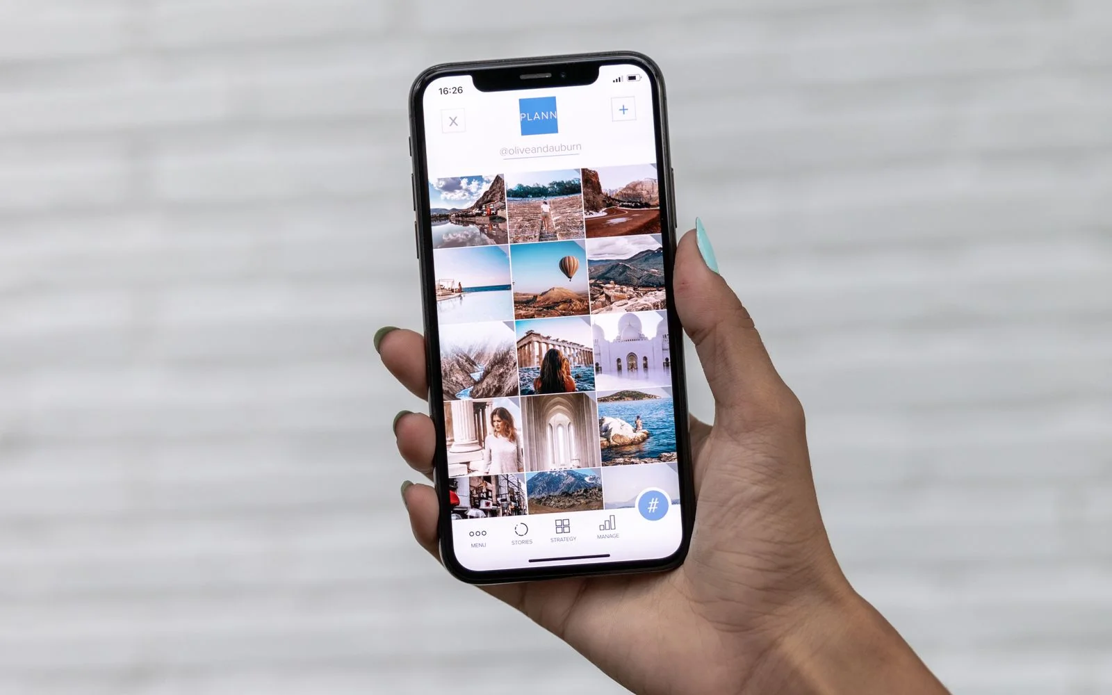 A hand holding a smartphone showing a gallery of travel photos