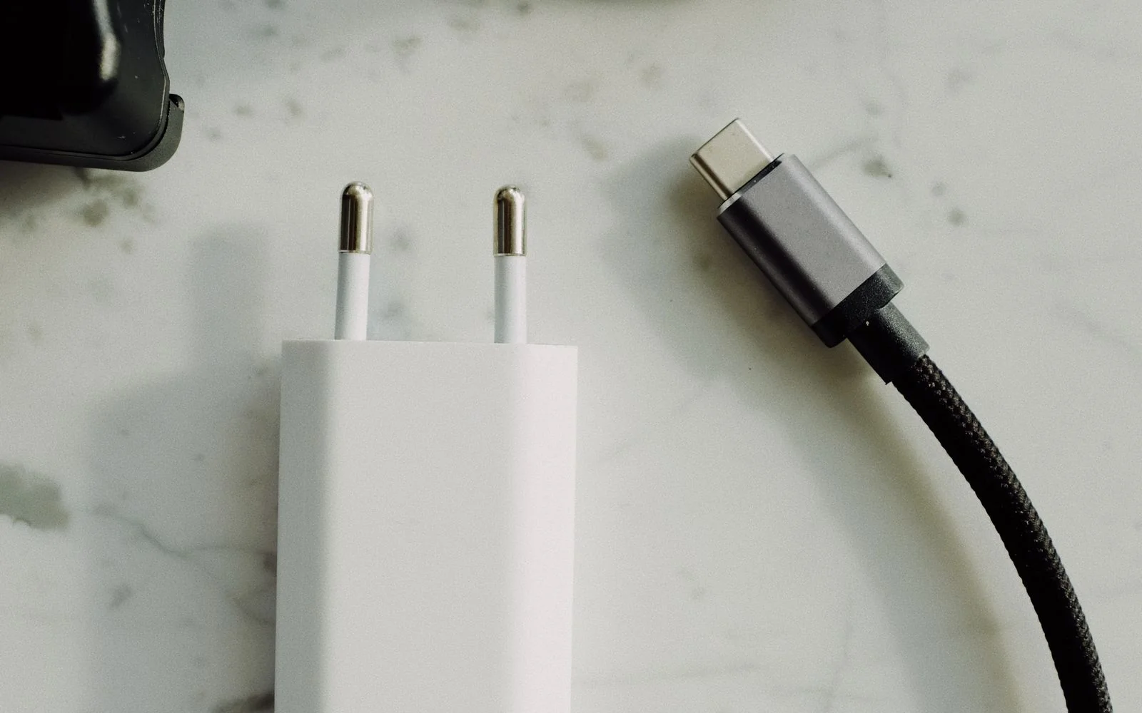A USB-C charger and plugs on a marble tabletop
